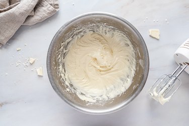 Whipped cream cheese frosting in a metal bowl.