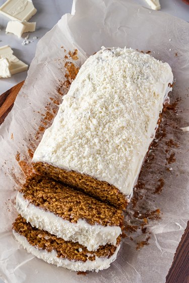 The pumpkin spice loaf topped with white cream cheese frosting and shredded white chocolate.