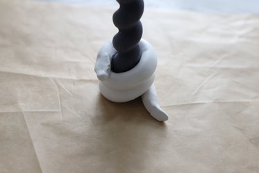 Clay snake coiled around a black spiral taper candle