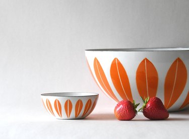 A large and mini white bowl patterned with long orange leaves around the exterior.