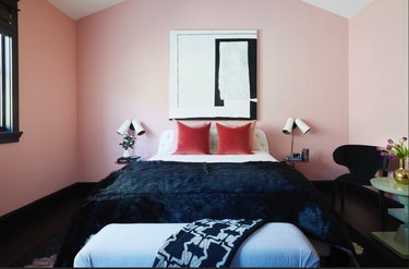 bedroom with pink walls, blue bench and black accents