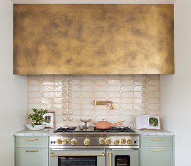 contemporary kitchen with mint green cabinets, large stove with a pink tiled backsplash