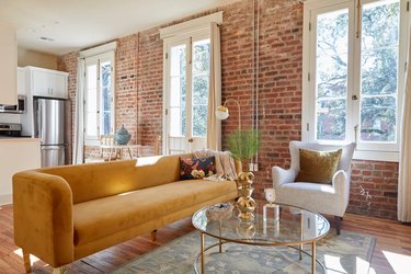 Terra cotta brick walled loft with caramel velvet sofa and white side chair.