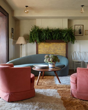 living room with cream and camel rug, pink club chairs and blue sofa