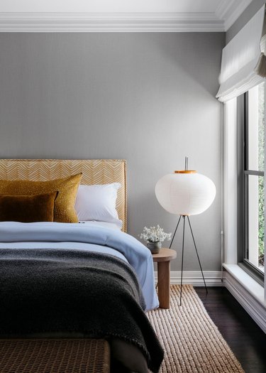 bedroom with gray walls blue bedding with yellow headboard and pillow
