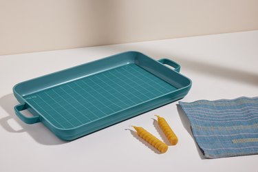 The Our Place Shabbat Set loaf pan with two candlesticks and a blue cloth on a white table.