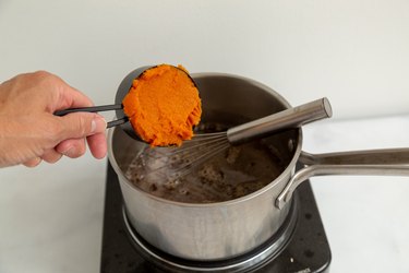 Adding pumpkin puree to saucepan