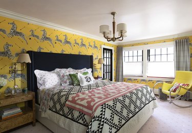 Bedroom with yellow, black and white zebra wallpaper by Scalamandré, black, white and pink bedding and a yellow side chair.
