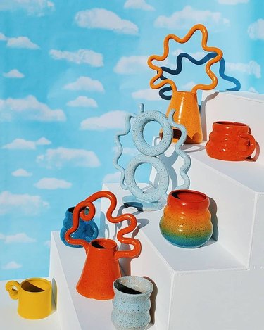 photo with cloud background and white steps with colorful ceramic mugs