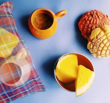 overhead shot of table with bag and ceramics and fruit and two pan dulce breads