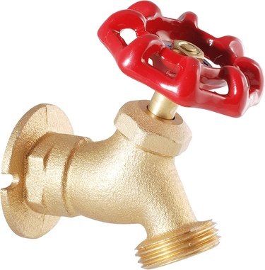A brass outdoor spigot with a red knob
