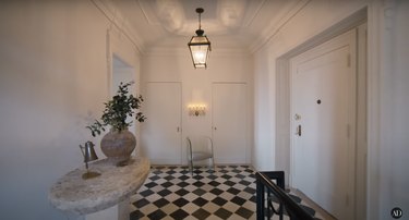 Nate Berkus and Jeremiah Brent's entryway from another angle, showing a snake-like sconce and large lantern pendant hanging from the ceiling.