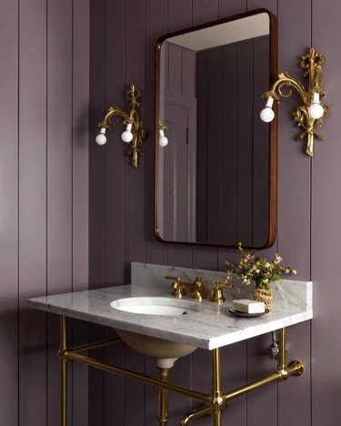 powder room with rich purple walls and gold fixtures
