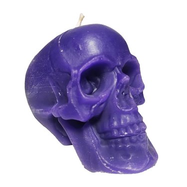 A purple candle in the shape of a skull over a white background