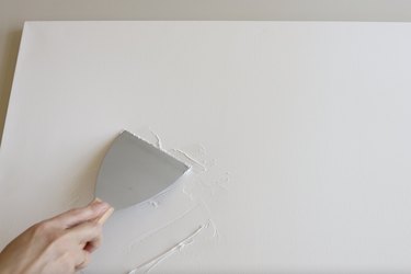 Spreading spackling on canvas with putty knife