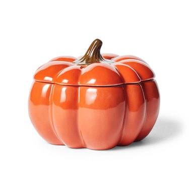 A shiny orange pumpkin jar with a lid and a brown stem sticking out of the top.