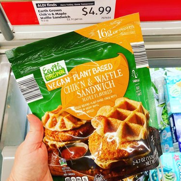 Hand holding the new Earth Grown’s Plant-Based Chik’n & Waffle Sandwich package in Aldi store