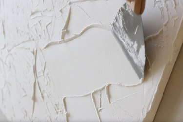 Dragging putty knife through spackling
