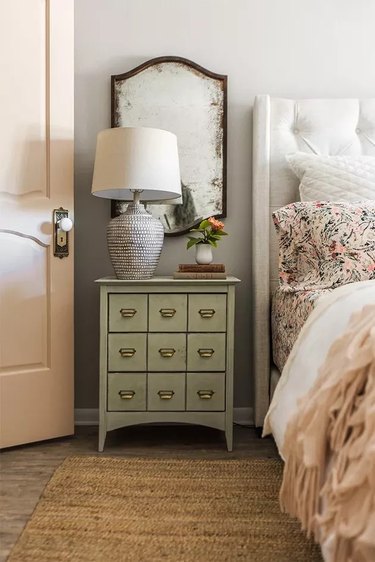 Bedroom with gray walls and blush pink bed sheets and door and green bedside cabinet