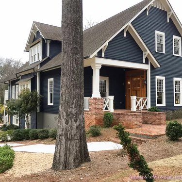 Side view of a house with navy siding and a red brick wall entry path