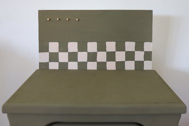 Plywood sheet painted green to match the nightstand with a checkerboard pattern added along the bottom