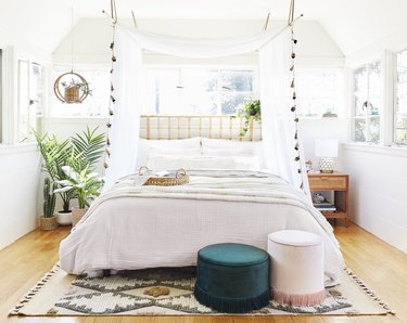 Bedroom with canopy, poufs, rug, plants