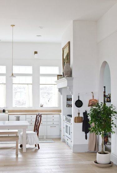 Open concept kitchen with white plaster walls, an arched doorway and hardwood floors.