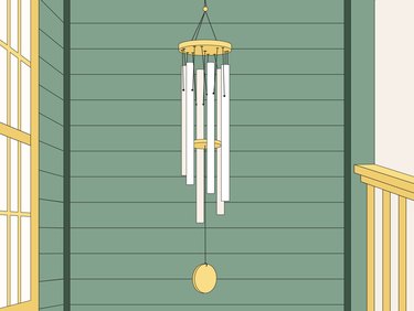 An illustration of a wind chime with silver pipes and yellow accents. It is shown on a front porch covered in green wood slats.