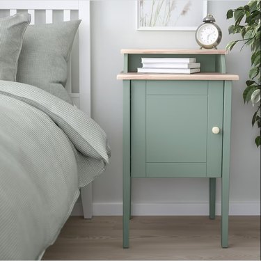 ikea nightstand in gray-green next to a matching bed