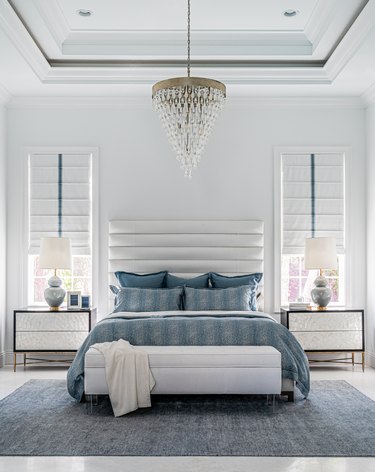 White bedroom with blue textured bedding and rug.