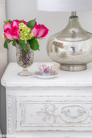 A white nightstand with pink roses and hydrangeas.
