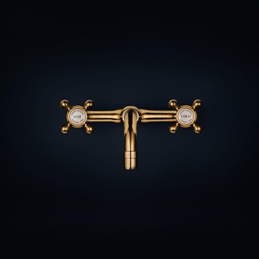 A gold Barber Wilsons faucet with hot and cold knobs.