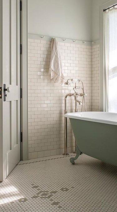 bathroom with sage green tub and ivory subway tile