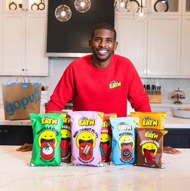 Chris Paul with Good Eat'n bags in a white kitchen with a Gopuff bag behind him