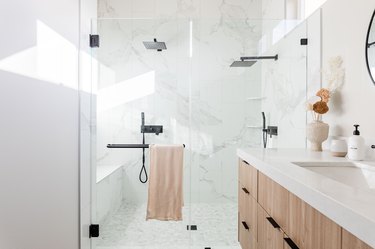 Bathroom with shower, two shower heads, wooden vanity.