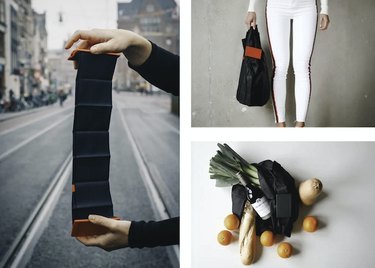 Hands folding down a foldable bag, a person dressed in all white holding a black tote, and a black tote laying on a countertop covered with wine, bread, oranges, and green onions.