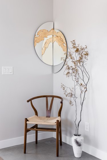 Accent chair, mirror, vase, branch.