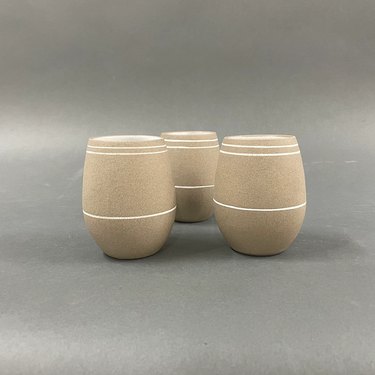 three ceramic cups in neutral color with white lines