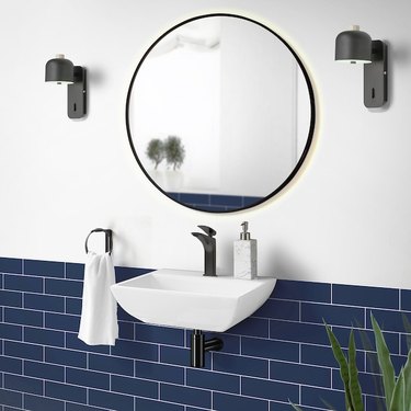 A white wall-mounted sink mounted on a blue subway tile wall