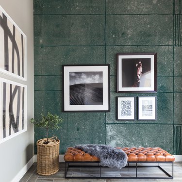 green concrete-textured gallery wall in front of leather daybed
