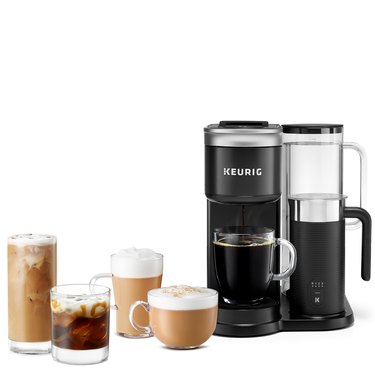 In front of an all white background, from left to right, is a tall glass of iced coffee, a small glass of iced coffee topped with a drizzle of caramel, a tall latte glass, a short latte glass, and a cup of black coffee resting on Keurig's K-Cafe SMART — a black and silver coffee brewer with a black and silver milk frother attached.
