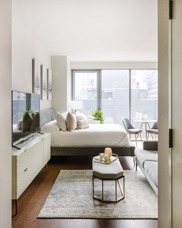 neutral studio apartment with bed next to living room and dining area