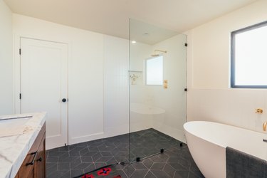 Large shower with frameless door, glass, and gray ceramic floor tile