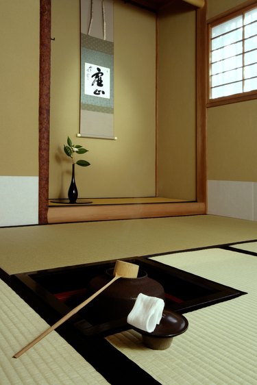 A tea house floor and wall with simple art showing a Japanese character.