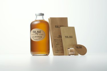 A bottle of the Pure Malt Whiskey next to brown packaging.
