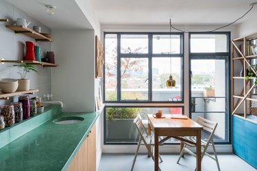 kitchen and dining area featuring shelves and pops of color with table near windows