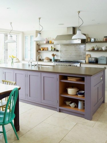 White kitchen with purple island and stainless steel appliances.