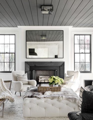 Living room with gray painted ceiling with shiplap, fireplace and white couches.