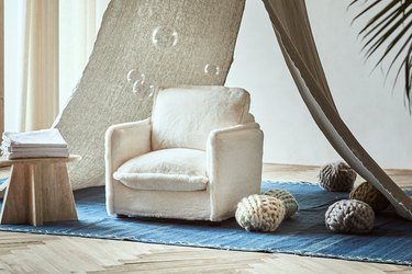 The mini Sixpenny Neva chair is a white cotton surrounded by knit yarn balls and bubbles in the air.