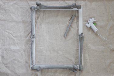 Hot gluing plastic bones around a white picture frame